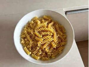 Pasta corta cotta e stesa in una ciotola per raffreddarsi prima di condire