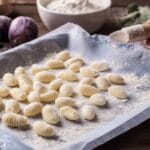 Gnocchi fatti in casa freschi, disposti su vassoio infarinato pronti per la cottura