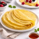 Crepes senza uova morbide e sottili, impilate su un piatto e servite con frutta fresca
