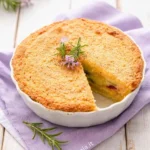 Gateau di patate cotto al forno con crosta dorata e porzione tagliata, decorato con rametti di rosmarino
