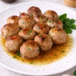 Polpette di carne fatte in casa, dorate e morbide, servite con il loro fondo di cottura