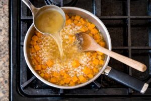 Brodo aggiunto al risotto alla zucca durante la cottura