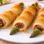Asparagi avvolti in pasta kataifi croccante, cotti al forno e serviti come antipasto su piatto bianco