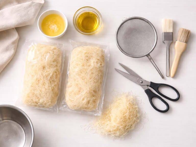 Attrezzi utili per cucinare con la pasta kataifi su piano di lavoro bianco
