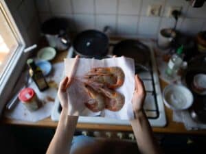 Gamberi crudi asciugati con carta da cucina prima di avvolgerli nella pasta kataifi