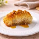 Kataifi ricetta greca cotto al forno, dolce tradizionale con pasta kataifi croccante, noci e sciroppo servito su piatto bianco