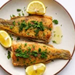 Pesce persico in scapece fritto e marinato con limone e prezzemolo su piatto bianco