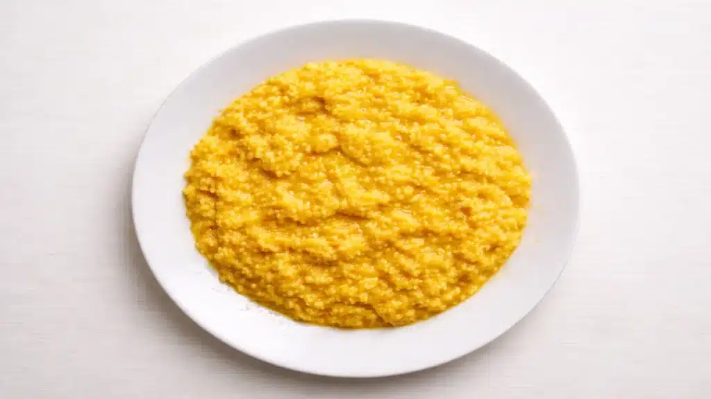 Risotto alla milanese cremoso allo zafferano su piatto bianco visto dall’alto