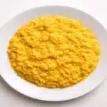 Risotto alla milanese cremoso allo zafferano su piatto bianco visto dall’alto
