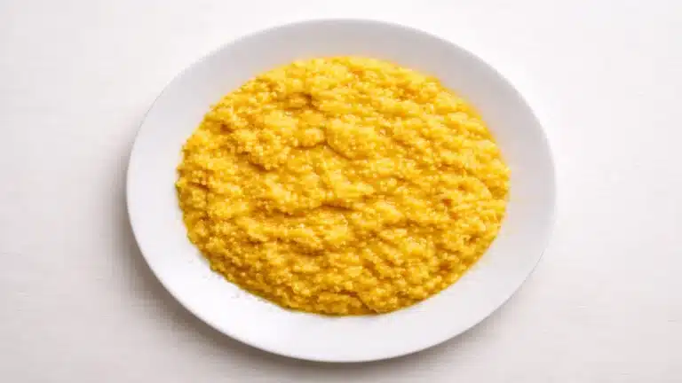 Risotto alla milanese cremoso allo zafferano su piatto bianco visto dall’alto